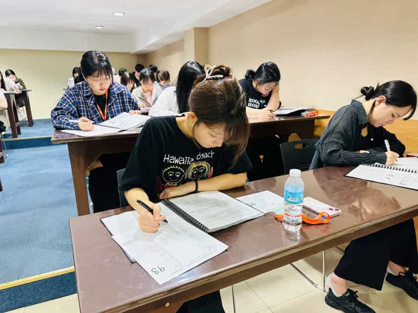CPILS students taking a paper-based mock exam in a large classroom