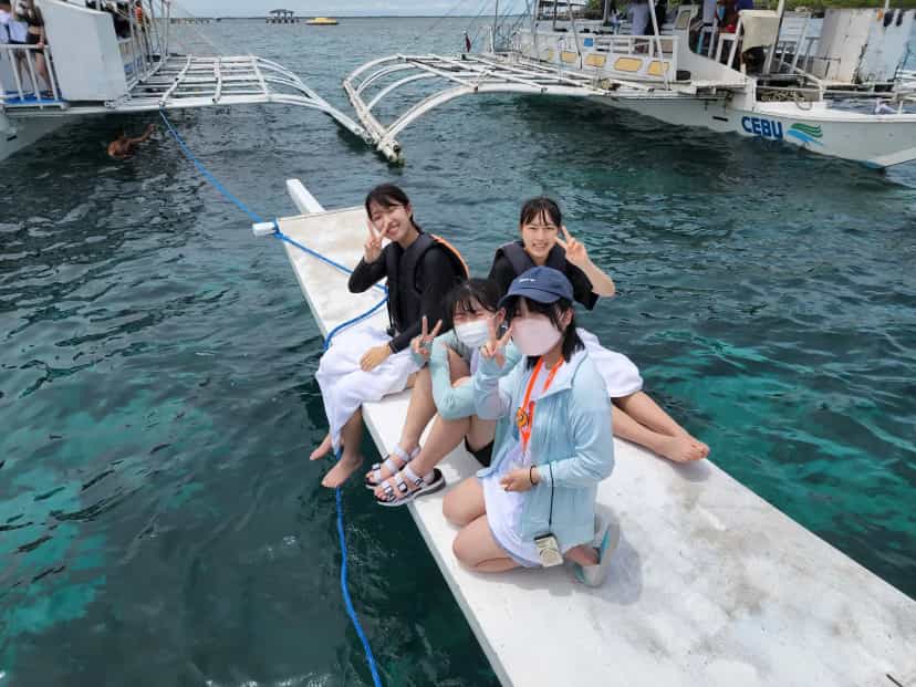 CPILS students island hopping, sitting on the bamboo outrigger of a bangka boat