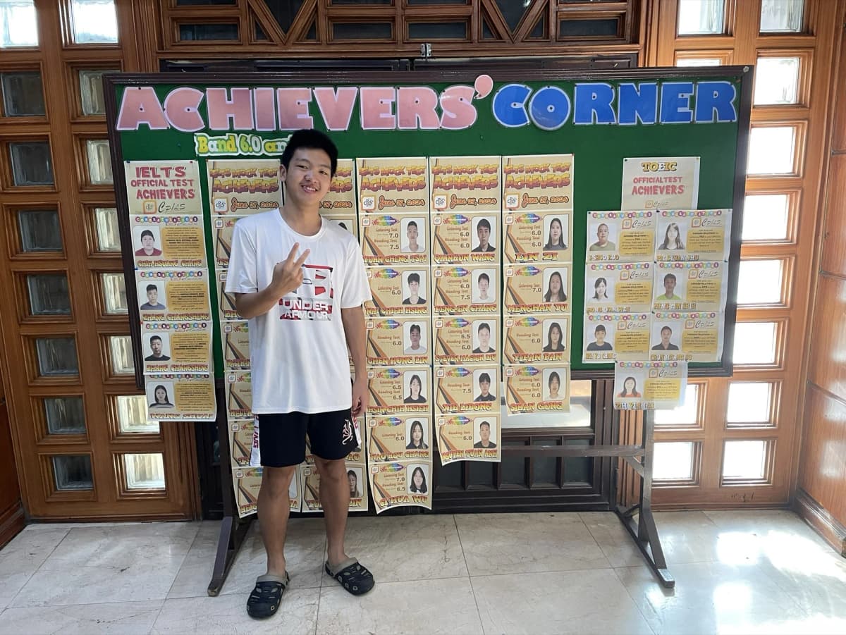 Anderson Tsai 站在 CPILS 校內 Achievers' Corner 公布欄前,欄上張貼 IELTS 模考達標學生名單
