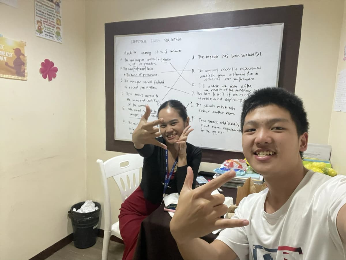 Anderson Tsai 與 CPILS 老師在教室白板前自拍,白板上是課堂筆記