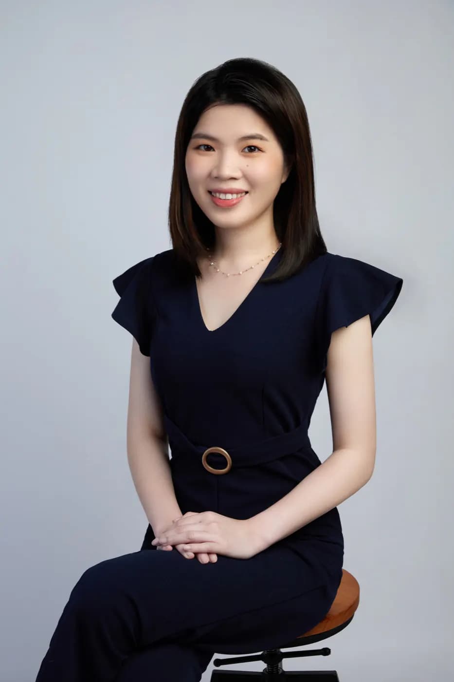 남색 원피스를 입고 연한 회색 배경 앞에 앉아 미소 짓는 Roseline의 프로필 사진