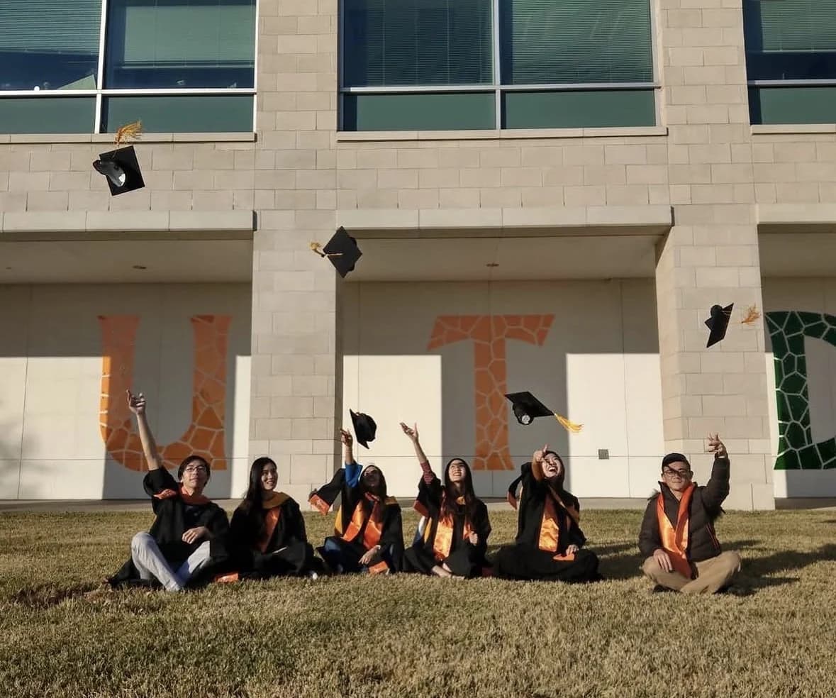 Yuiti 與同學身穿畢業袍,在 UT Dallas 校園草地上拋帽慶祝畢業